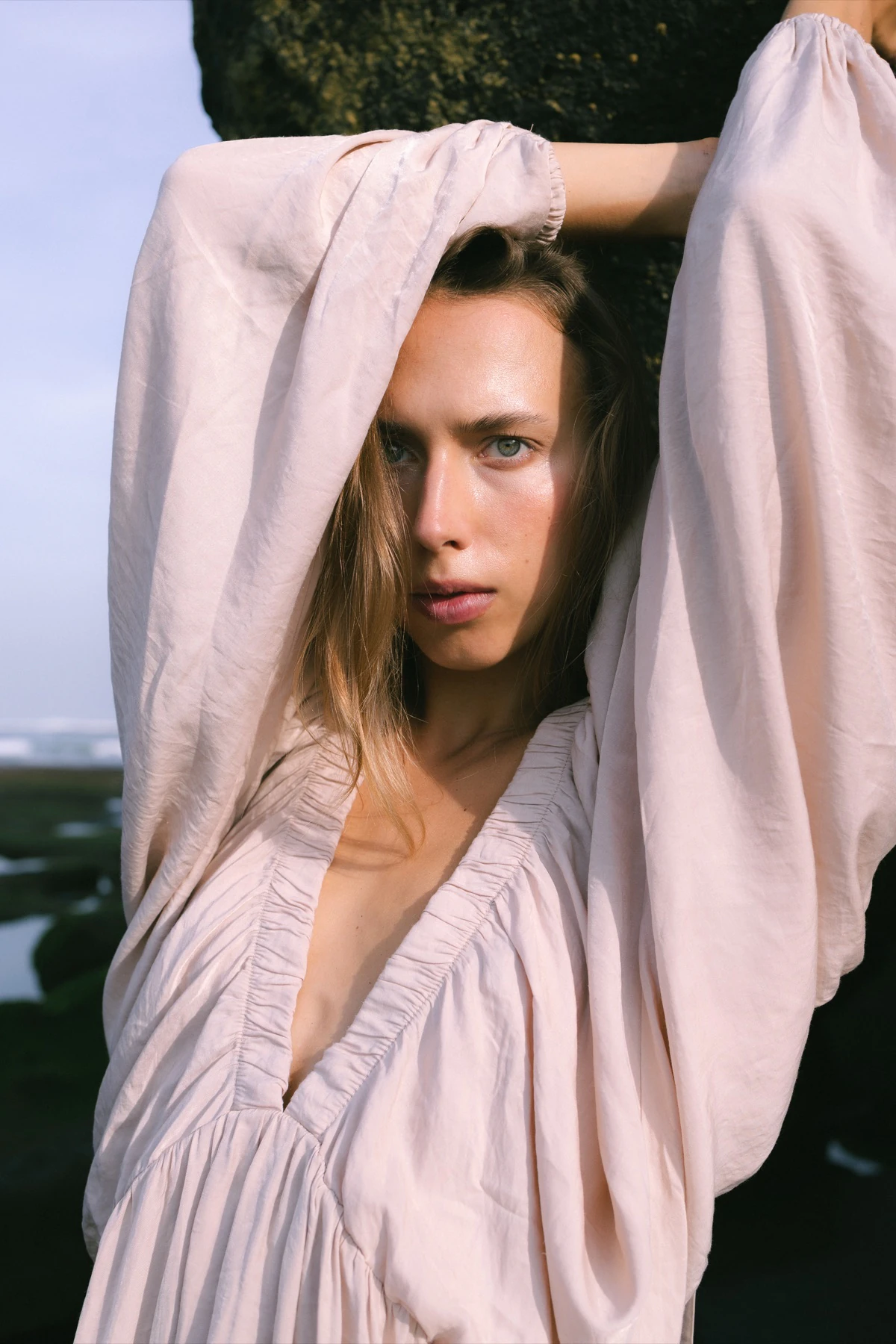 A woman framed by the sleeves of a pale dress